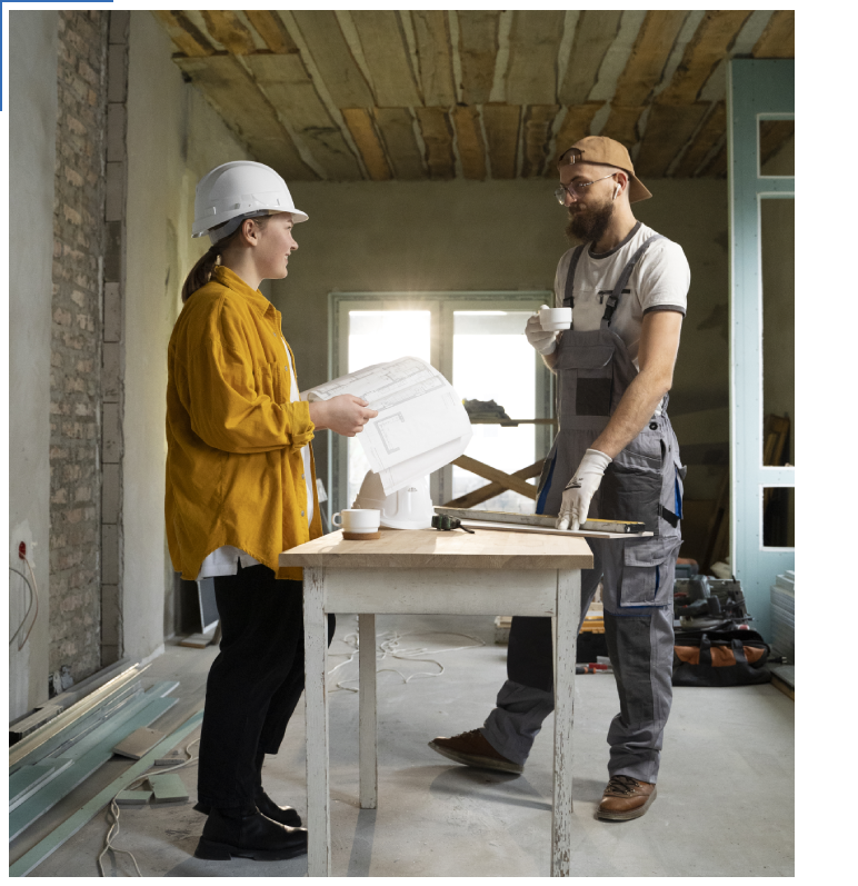 Two people standing in a room with construction equipment.